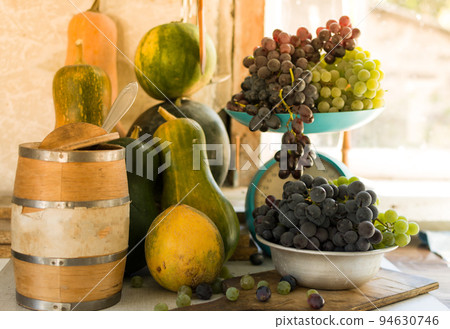 Autumn still life with pumpkins, melons, watermelon, grapes on a scale and in a metal bowl on a wooden white table. Autumn harvest concept. Happy Thanksgiving. Selective focus. Template for design. 94630746