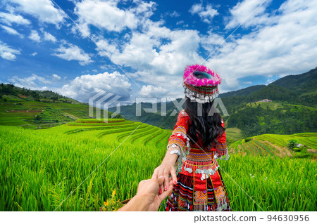Hmong ethnic minority holding man's hand and leading him to rice terraces in Mu Cang Chai, Yen Bai, Vietnam. 94630956