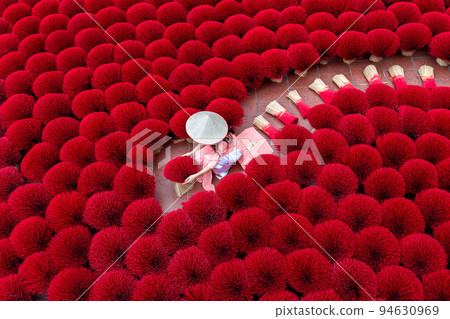 Asian woman wearing ao dai dress with Incense sticks drying outdoor in Hanoi, Vietnam. Asian woman wearing ao dai dress with Incense sticks drying outdoor in Hanoi, Vietnam. 94630969