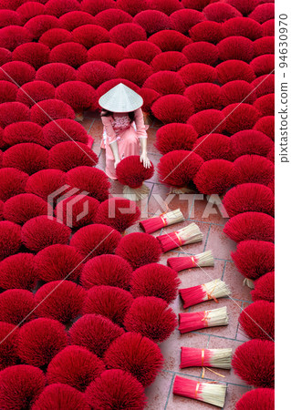 Asian woman wearing ao dai dress with Incense sticks drying outdoor in Hanoi, Vietnam. Asian woman wearing ao dai dress with Incense sticks drying outdoor in Hanoi, Vietnam. 94630970