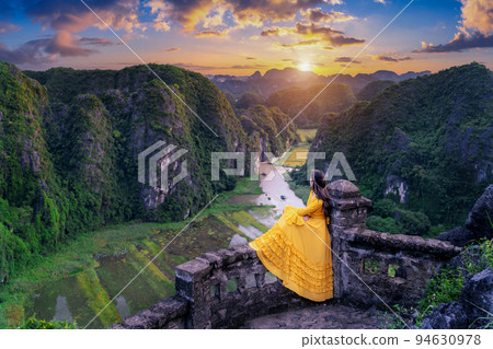 Woman tourist sitting on Hang Mua viewpoint. Popular tourist attraction at Tam Coc, Ninh Binh. Vietnam. 94630978