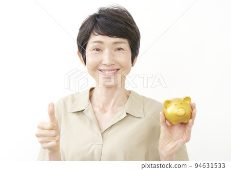 一位中年婦女拿著一個存錢罐並給出一個好兆頭白色背景 94631533