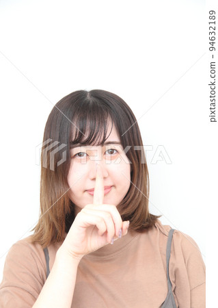 一位年輕女子的特寫，她一邊看著相機，一邊把食指放在嘴上 94632189