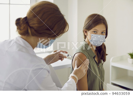 Nurse giving flu, covid or monkeypox vaccine injection to child patient in face mask Nurse giving flu, covid or monkeypox vaccine injection to child patient in face mask 94633059