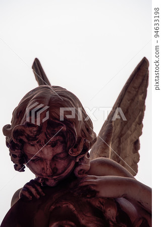 Statue of an angel with wings against a white background. 94633198