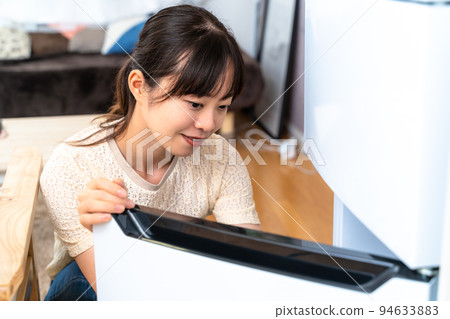A young woman who opens a fridge A young woman who opens a fridge 94633883