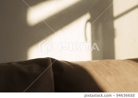 indoor shot of a couch with window frame shadow on it and on the wall behind it indoor shot of a couch with window frame shadow on it and on the wall behind it 94636688