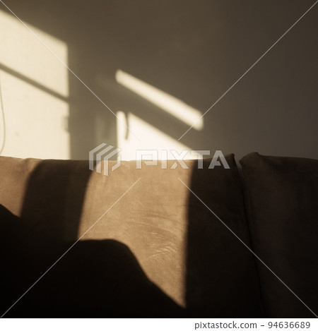 indoor shot of a couch with window frame shadow on it and on the wall behind it indoor shot of a couch with window frame shadow on it and on the wall behind it 94636689