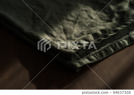 green linen napkin on walnut wood table with sunset light 94637308