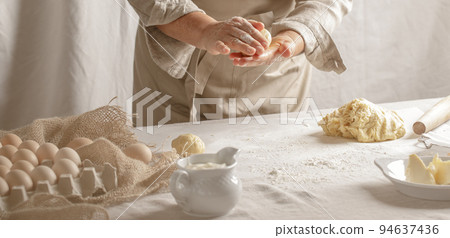 Womens hands, flour and dough. A woman is preparing a dough for home baking. Concept of home cooking with organic and natural ingredients. Zero waste concept Womens hands, flour and dough. A woman is preparing a dough for home baking. Concept of home cooking with organic and natural ingredients. Zero waste concept 94637436