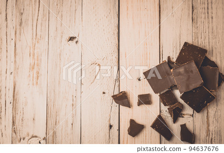 dark chocolate without sugar and gluten free for diabetics and allergics. Black chocolate broken into pieces lies on a white painted table in a rustic style. Dark toning. Copy space. dark chocolate without sugar and gluten free for diabetics and allergics. Black chocolate broken into pieces lies on a white painted table in a rustic style. Dark toning. Copy space. 94637676