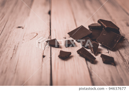 dark chocolate without sugar and gluten free for diabetics and allergics. Black chocolate broken into pieces lies on a white table in a rustic style. Dark toning and vignette. dark chocolate without sugar and gluten free for diabetics and allergics. Black chocolate broken into pieces lies on a white table in a rustic style. Dark toning and vignette. 94637677