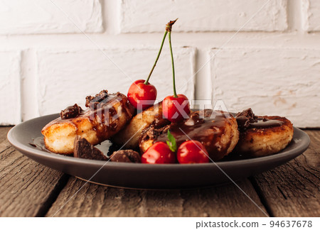 Breakfast Food Tasty Concept. Cheesecakes, cheesecakes, curd pancakes with cherries and chocolate on a black background from a concrete table and a white brick wall. Close-up.Healthy Food Breakfast Food Tasty Concept. Cheesecakes, cheesecakes, curd pancakes with cherries and chocolate on a black background from a concrete table and a white brick wall. Close-up.Healthy Food 94637678