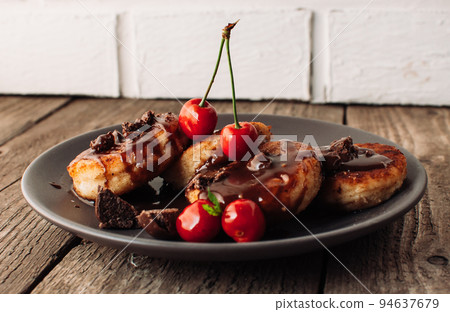 Breakfast Food Tasty Concept. Cheesecakes, cheesecakes, curd pancakes with cherries and chocolate on a black background from a concrete table and a white brick wall. Close-up.Healthy Food 94637679