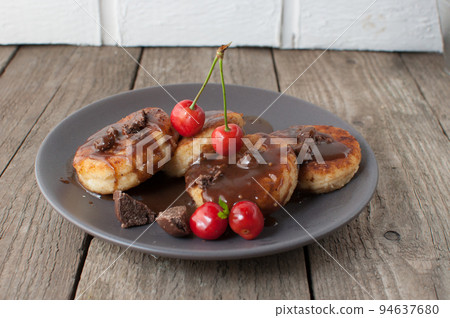 Gourmet breakfast - curd pancakes, cheesecakes, curd pancakes with cherries and chocolate in a brown plate. Wholesome dessert on a wooden table in a rustic style. Selective focus Gourmet breakfast - curd pancakes, cheesecakes, curd pancakes with cherries and chocolate in a brown plate. Wholesome dessert on a wooden table in a rustic style. Selective focus 94637680