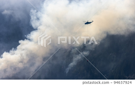 Wildfire Service Helicopter flying over BC Forest Fire and Smoke on the mountain near Hope 94637924