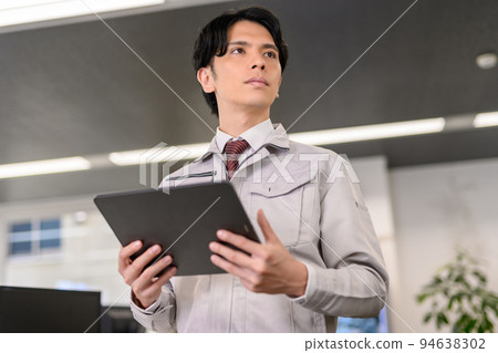 一個穿著工作服的男人用平板電腦檢查 94638302