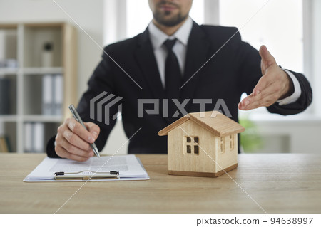 Realtor man pointing model of house located on table during signing contract for sale real estate Realtor man pointing model of house located on table during signing contract for sale real estate 94638997