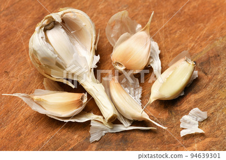 ripe garlic head and cloves on a rustic wooden background, delicious and healthy food 94639301