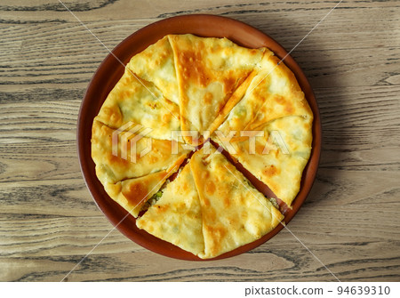 One placinda on a wooden table. Flour products of Moldovan cuisine include various fried pies with stuffing, cottage cheese or potatoes, cabbage, etc. One placinda on a wooden table. Flour products of Moldovan cuisine include various fried pies with stuffing, cottage cheese or potatoes, cabbage, etc. 94639310