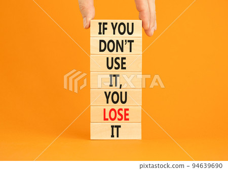 Use or lose symbol. Concept words If you do not use it you lose it on wooden blocks on a beautiful orange background. Businessman hand. Business motivational and use or lose concept. 94639690