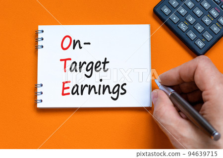 OTE on-target earnings symbol. Concept words OTE on-target earnings on white note on a beautiful orange background. Businessman hand. Business and OTE on-target earnings concept. Copy space. 94639715