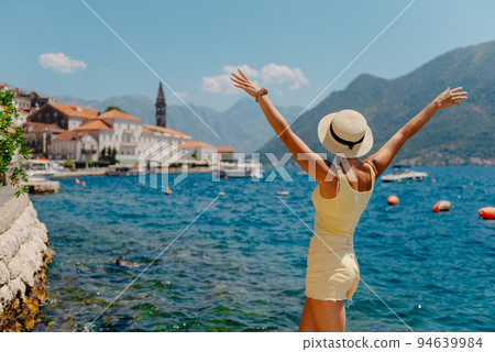 Summer photo shoot on the streets of Kotor, Montenegro. Beautiful girl in white dress and hat. smiling tourist girl with hat. Spectacular view of Montenegro with copy space. fashion outdoor photo of 94639984