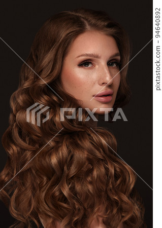 Beautiful brown-haired girl with a perfectly curls hair, and classic make-up. Beauty face and hair. 94640892
