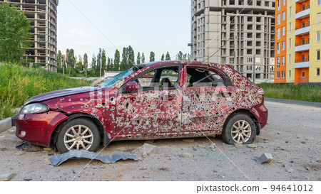 Damaged and destroyed civilian car with shrapnel holes from Russian missile in a war zone in Kharkiv, Ukraine Damaged and destroyed civilian car with shrapnel holes from Russian missile in a war zone in Kharkiv, Ukraine 94641012