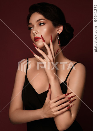 Beautiful redhair model: curls, bright gold makeup, long nails and red lips. The beauty face. Manicure disign 94641272