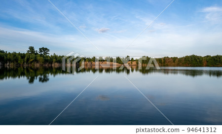 Cold summer morning in the forest with lake, forest reflection and sunset or sunrise on the water Cold summer morning in the forest with lake, forest reflection and sunset or sunrise on the water 94641312