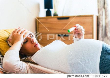 Pregnancy fever temperature check. Pregnant woman holding thermometer, check fever flu temperature. Pregnancy girl sick. Concept maternity, pregnant, childbirth. 94641377