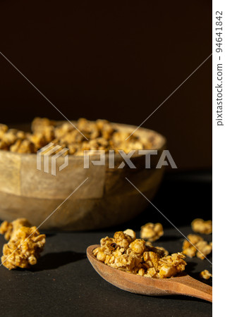 Homemade granola with nuts and seeds in eco tableware wooden bowl. Healthy snack on breakfast. Muesli from oatmeal, raisins, honey, cranberry, flax, almond, cashew, freshly baked  94641842