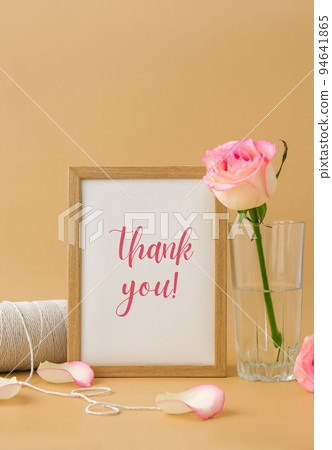 Wooden frame with greeting card text THANK YOU delicate pink roses, spool of white cotton rope on beige background. Minimal trendy composition. Romantic pastel pink rose flowers. Neutral earth tones 94641865