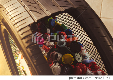 Public place collecting in car tire full of colorful plastic bottle cups, handful of waste of plastic lids. Recycling. Collecting bottle caps. Environment concept plastic bottle cap that is left from 94641935