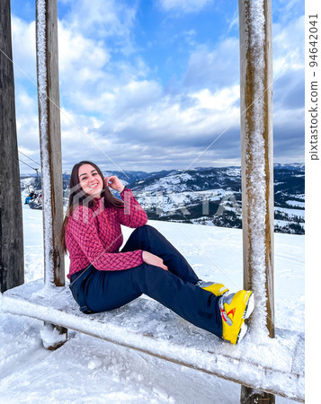 Shot of a skier woman sitting on the ski slope resting relaxing extreme recreation active lifestyle activity. Female skier on a slope in the mountains. Winter active sport Shot of a skier woman sitting on the ski slope resting relaxing extreme recreation active lifestyle activity. Female skier on a slope in the mountains. Winter active sport 94642041