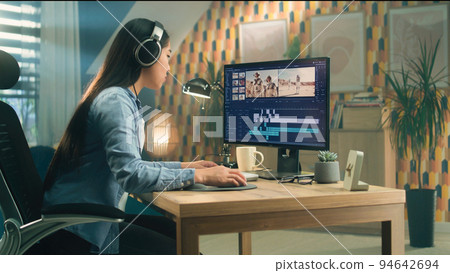 Woman in headset editing video at home 94642694