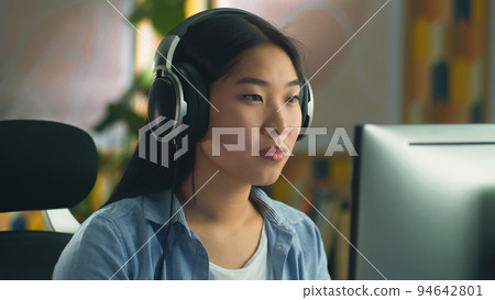Asian woman in headset working on pc 94642801