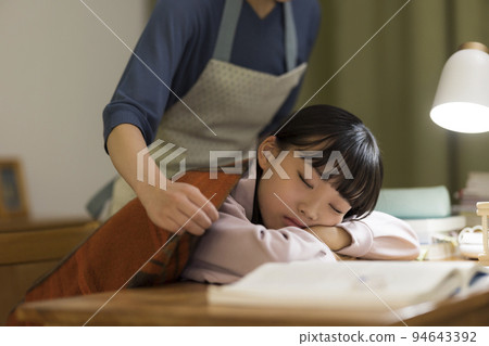 A mother who puts a blanket on her daughter who falls asleep at her study desk Junior high school student High school student A mother who puts a blanket on her daughter who falls asleep at her study desk Junior high school student High school student 94643392