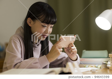 A girl studying while looking at a smartphone Junior high school high school student A girl studying while looking at a smartphone Junior high school high school student 94643399