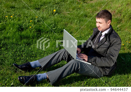 man with a laptop on the grass man with a laptop on the grass 94644437