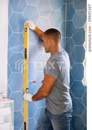 Man using spirit level on wall, working on home improvement 94645167