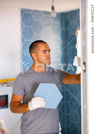 Man laying tile in bathroom Man laying tile in bathroom 94645227