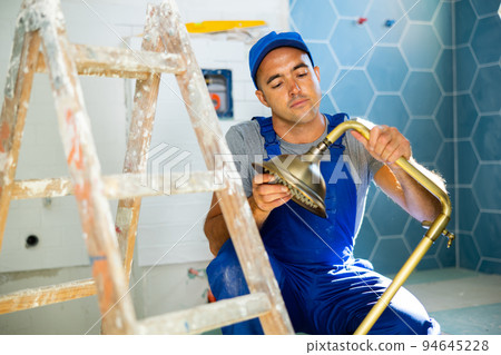 Repairman assembling shower in bathroom of new apartment Repairman assembling shower in bathroom of new apartment 94645228