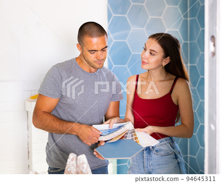 Husband and wife together choose color of ceramic tiles according to color patterns 94645311