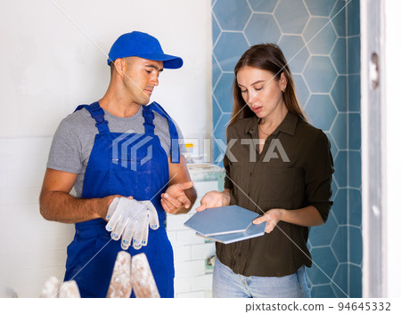Tile setter discussing works in bathroom with woman Tile setter discussing works in bathroom with woman 94645332