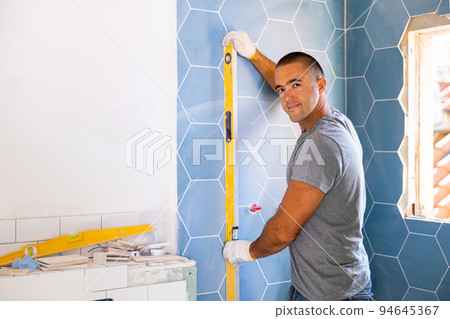 Portrait of young man dressing casual clothes using manual level in process of renovation 94645367