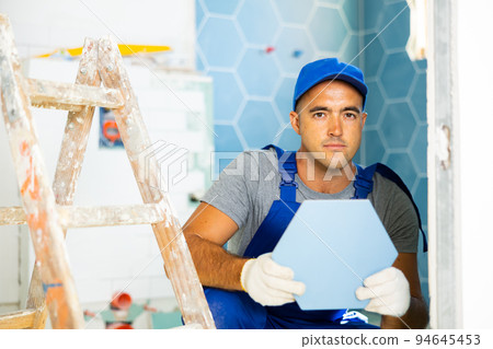 Repairman working in bathroom in apartment, laying tile 94645453