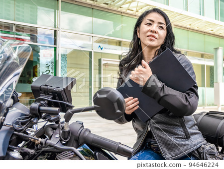 騎著大型巡洋艦自行車通勤 一位拿著筆記本電腦的女騎手 騎著大型巡洋艦自行車通勤 一位拿著筆記本電腦的女騎手 94646224