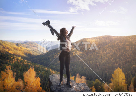 a female photographer at the top of the mountain spread her arms in joy of freedom and space. Landscape shooting of nature and travel concept in autumn a female photographer at the top of the mountain spread her arms in joy of freedom and space. Landscape shooting of nature and travel concept in autumn 94647083